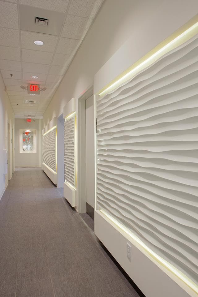 Art Diffusion wave panels lit from above along a long corridor wall.