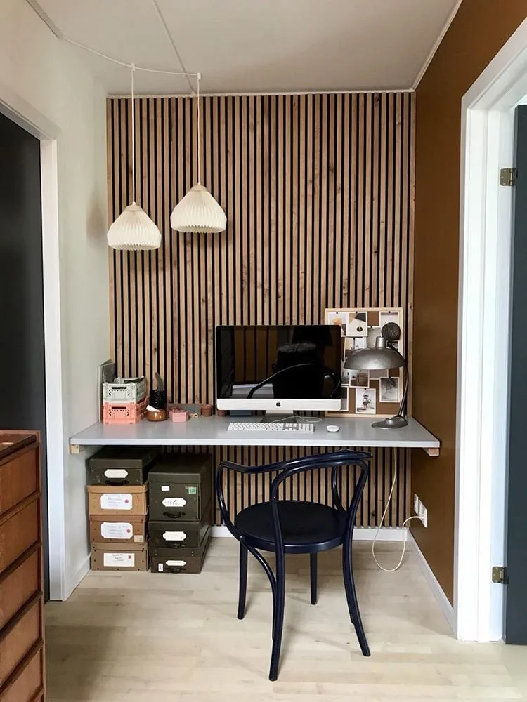 An Akupanel wall behind a home office desk with pendant lights.