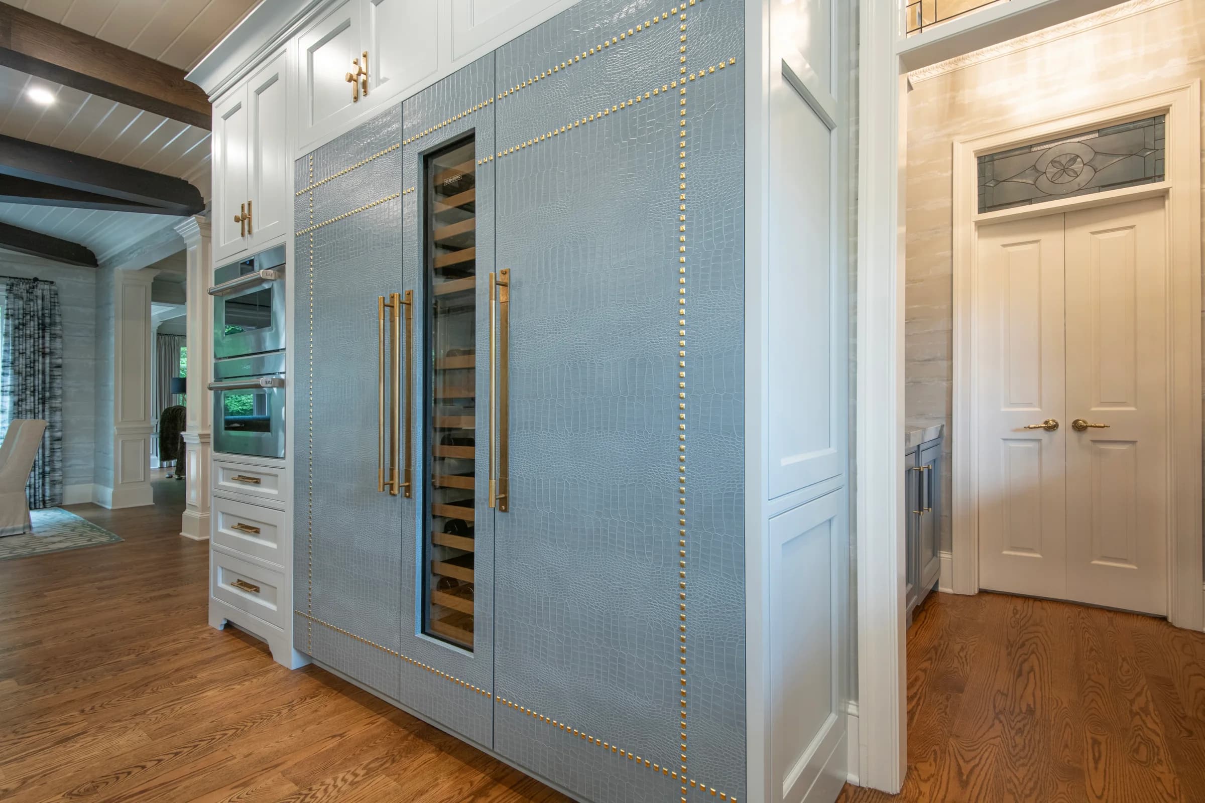 Kitchen pantry and refrigerator wall clad in grey EcoDomo recycled leather veneer with nailhead trim.