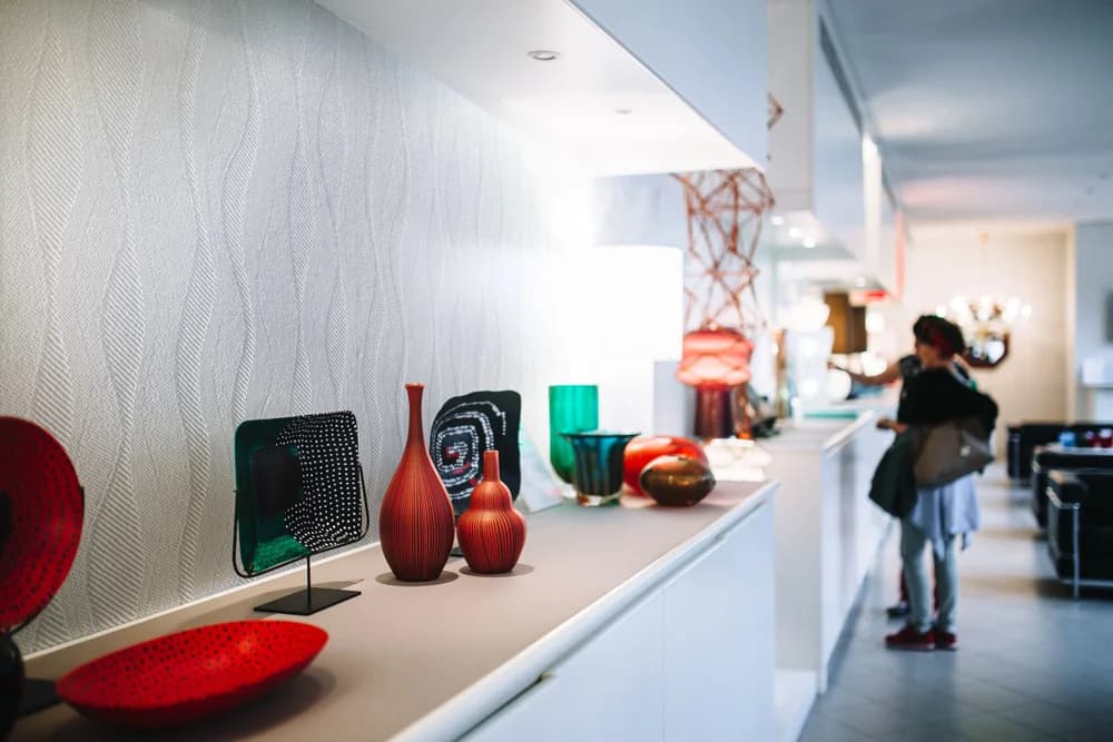 Gallery corridor with a white Novelio Decoration Undulation wave texture behind a display shelf.