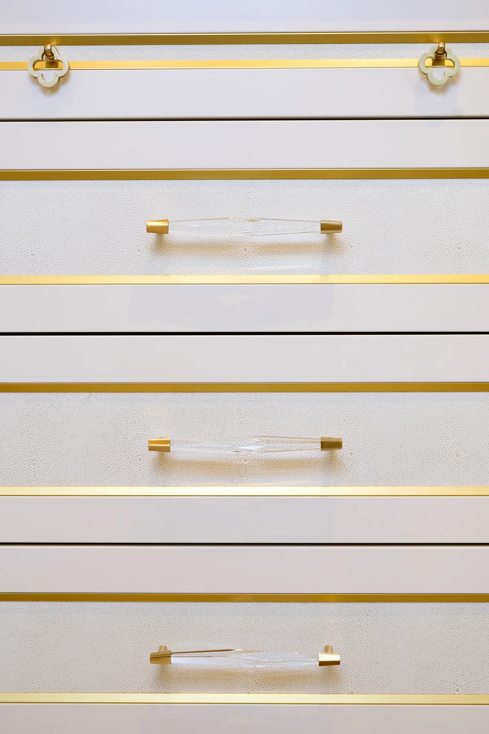 White recycled leather veneer drawer fronts with brass pulls.