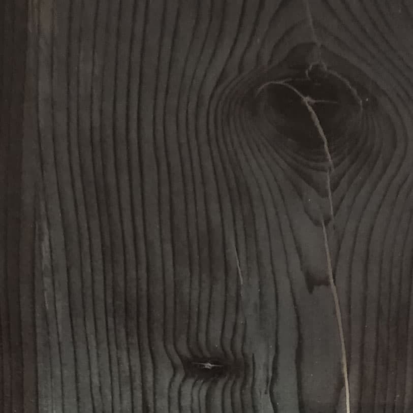 A woodgrain laminate pattern in black tones, defined by natural grain movement and layered tonal variation